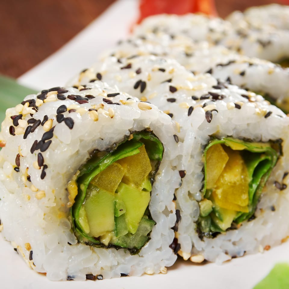 Close-up of Japon's sushi rolls with avocado, lettuce, and yellow filling, topped with sesame seeds.